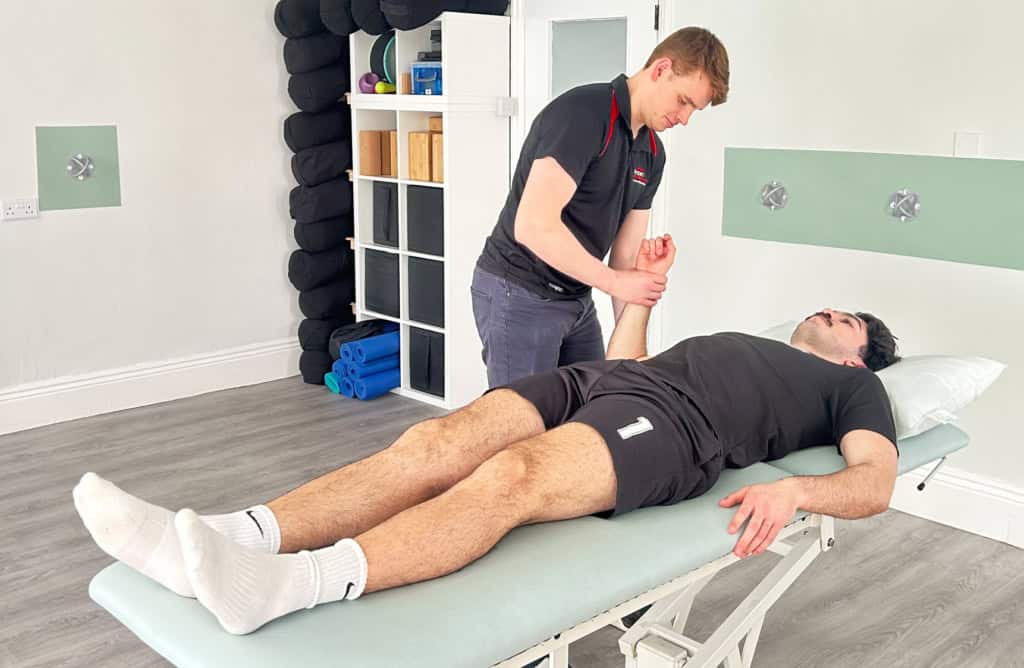 Physiotherapist raising a patient's arm to assess his shoulder