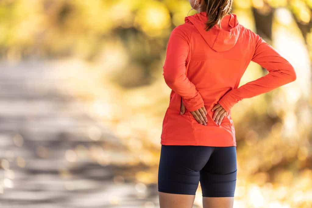 Runner with both hands on her lower back and pelvis