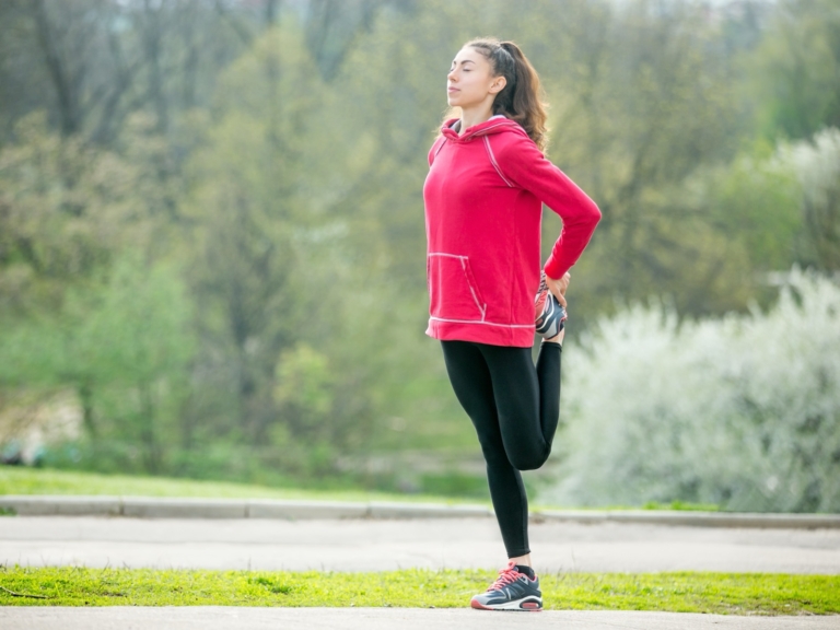 Woman stretching her thigh before a run in the park