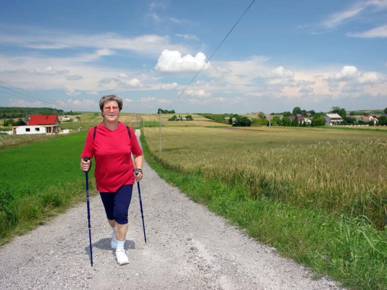 Older woman Nordic walking along a farm track