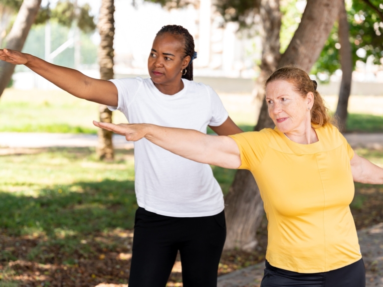 Two women practising Tai Chi in a park